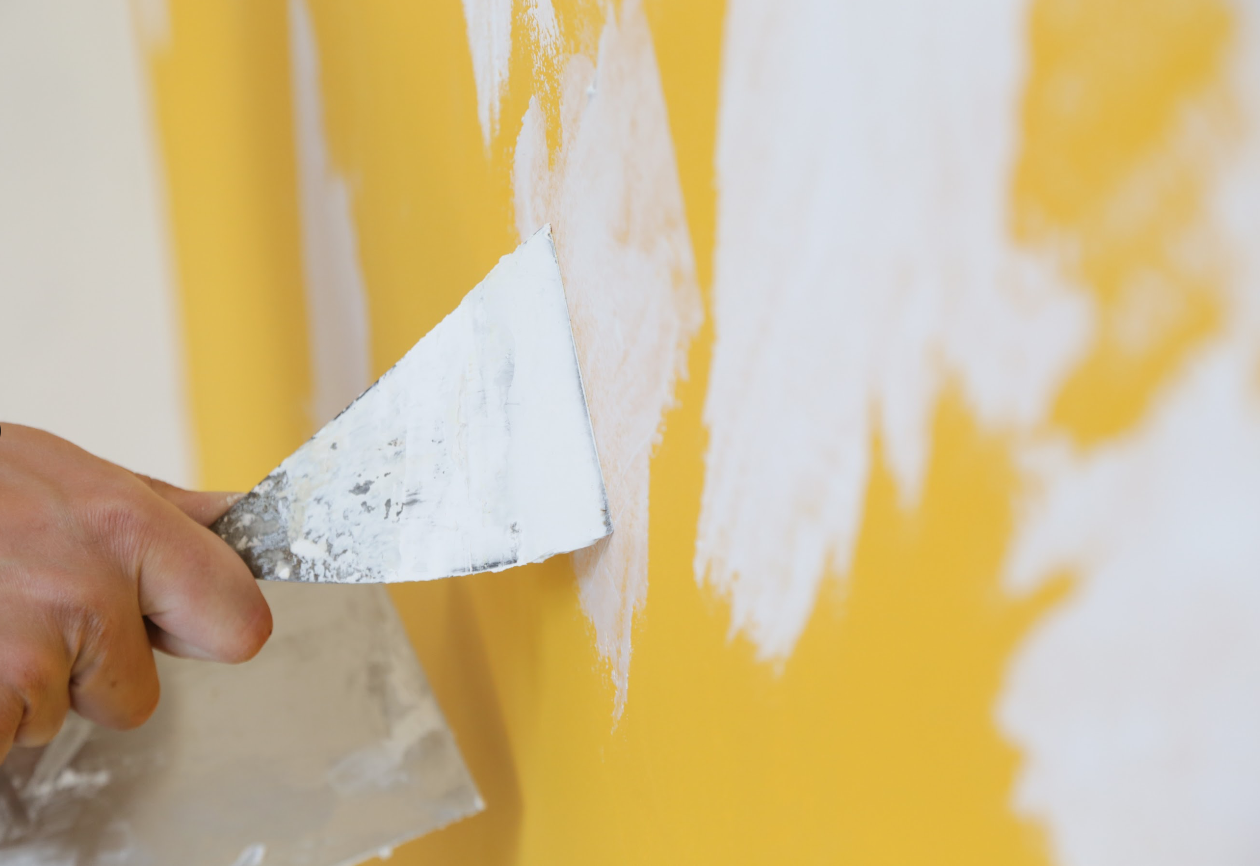 yellow wall someone using filler on holes