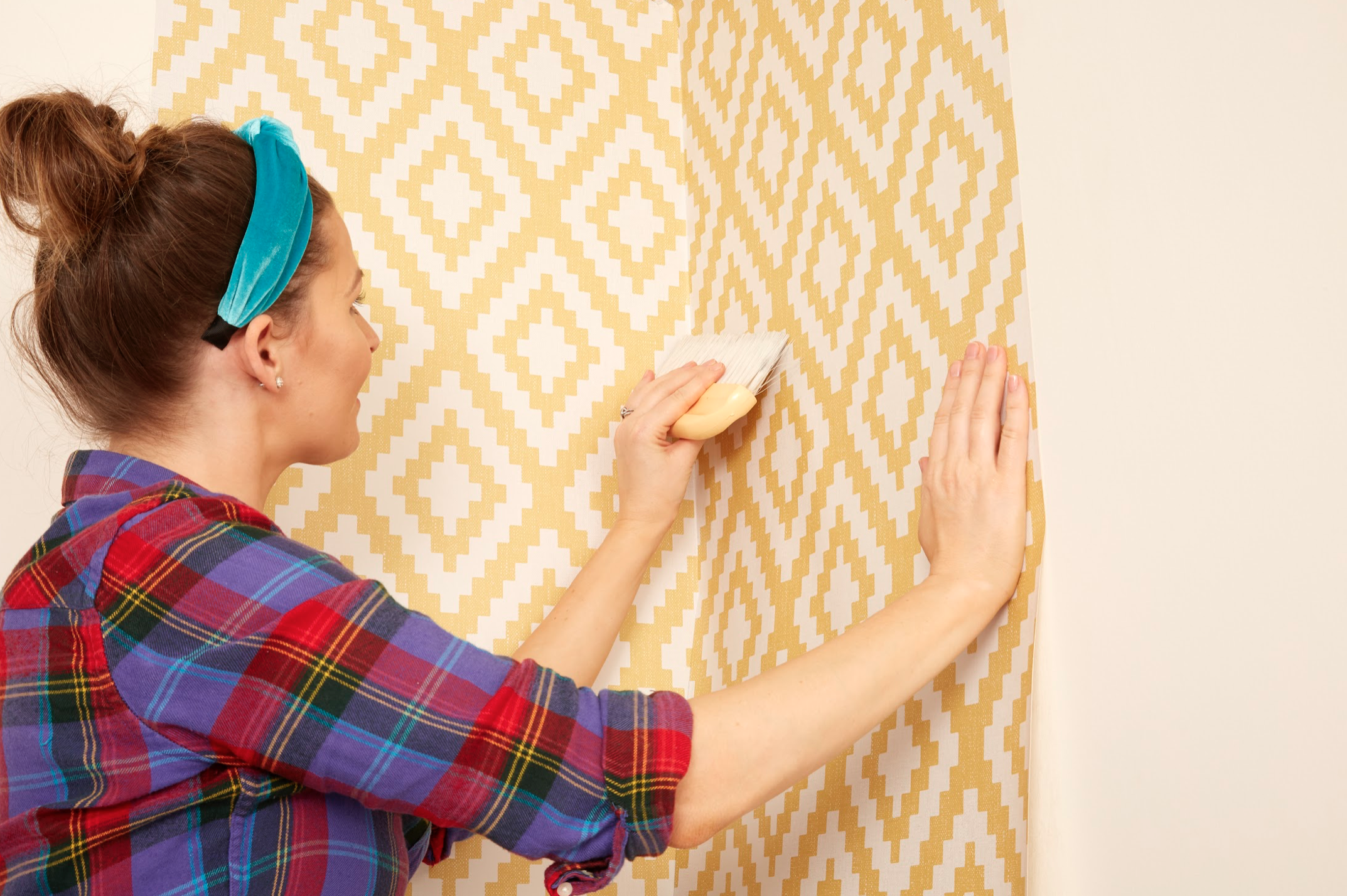 person using brush to hang wallpaper